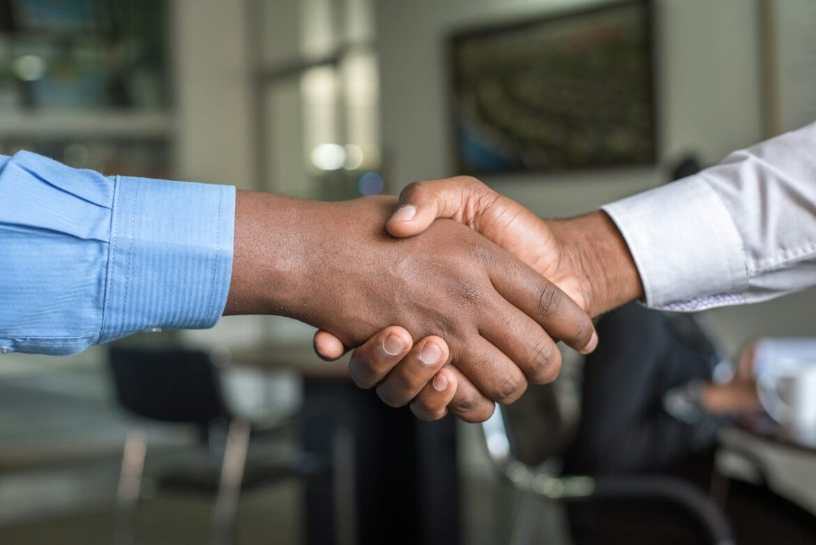 Two people shaking hands across a desk after a job interview